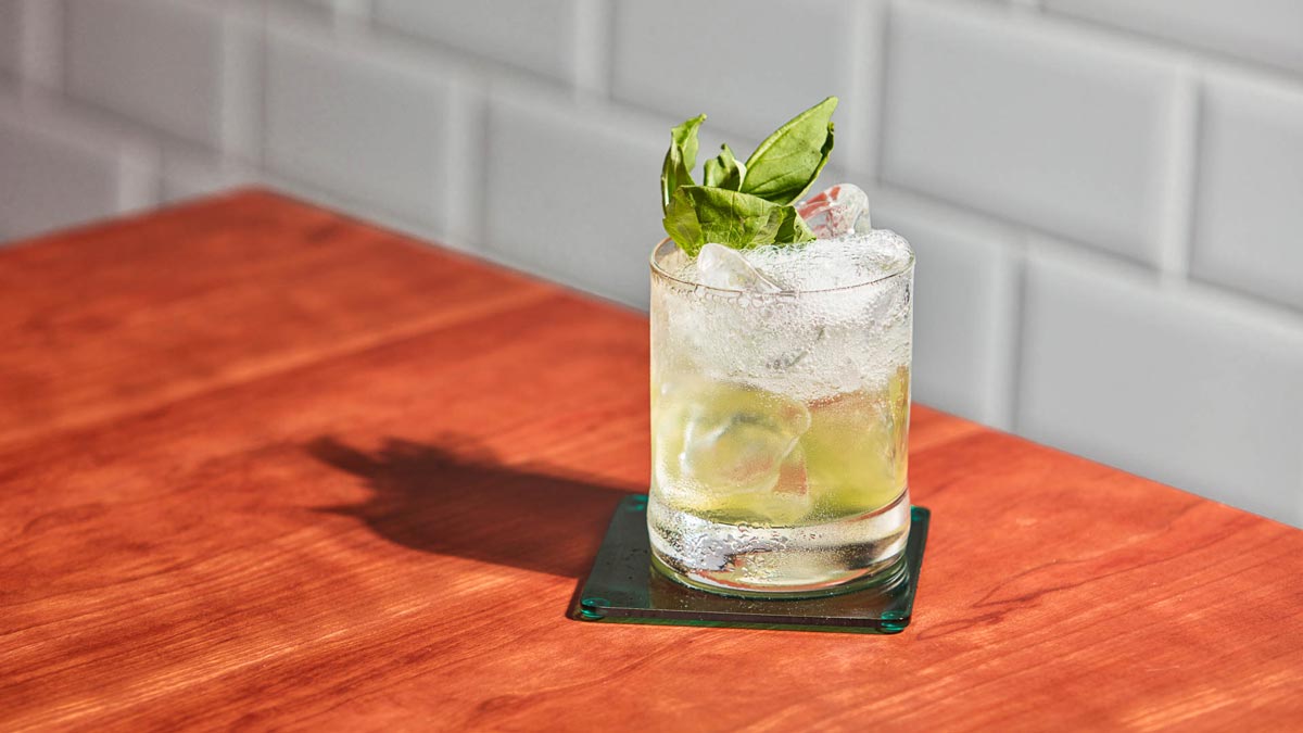 Glass of Botanist Sparkler on a wooden table against a tiled wall