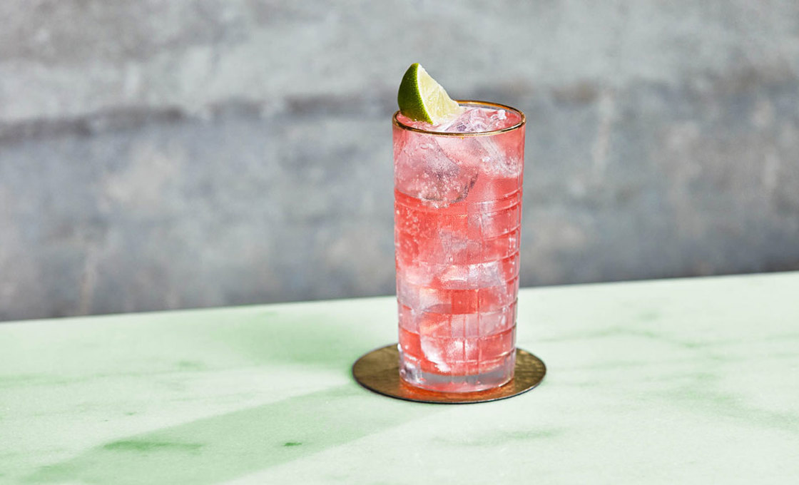 A glass of Cranberry and Lime Lemonade on a table outdoors