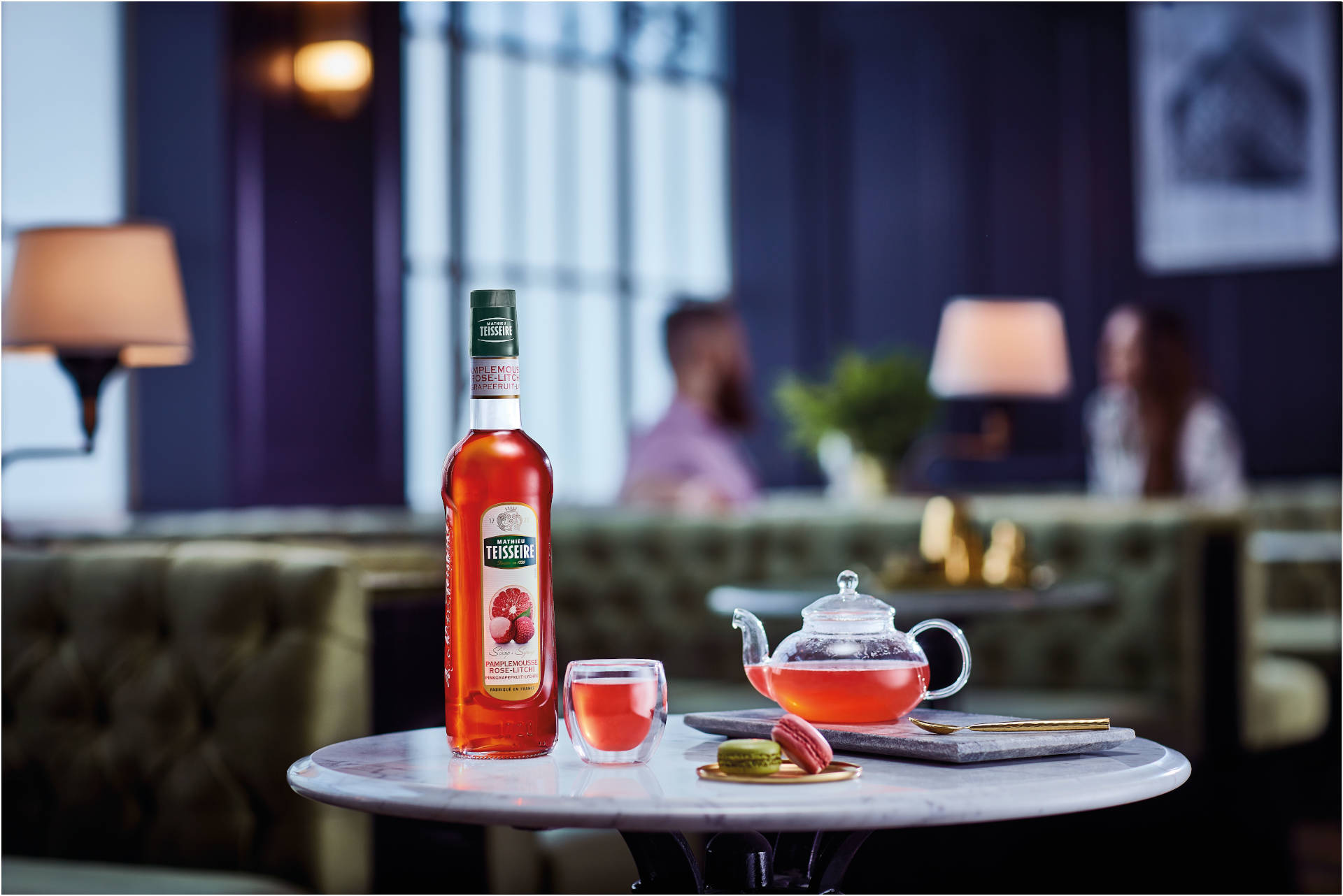 A glass of Asian spirit with glass teapot, macarons, and a bottle of Mathieu Teisseire Pink Grapefruit Lychee  syrup