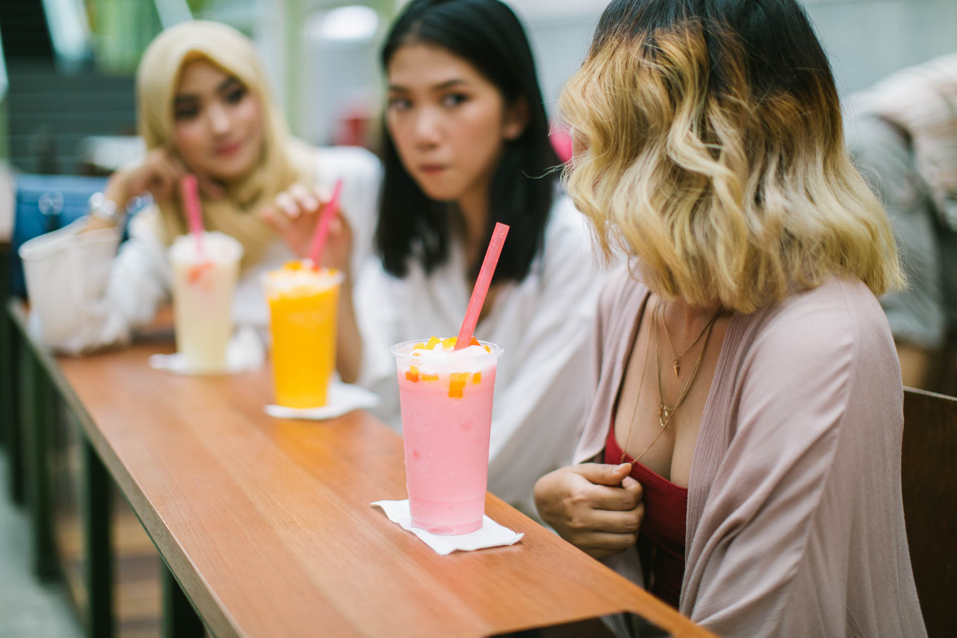 Multi-ethnic group of women sitting in the cafe and drinking milkshakes