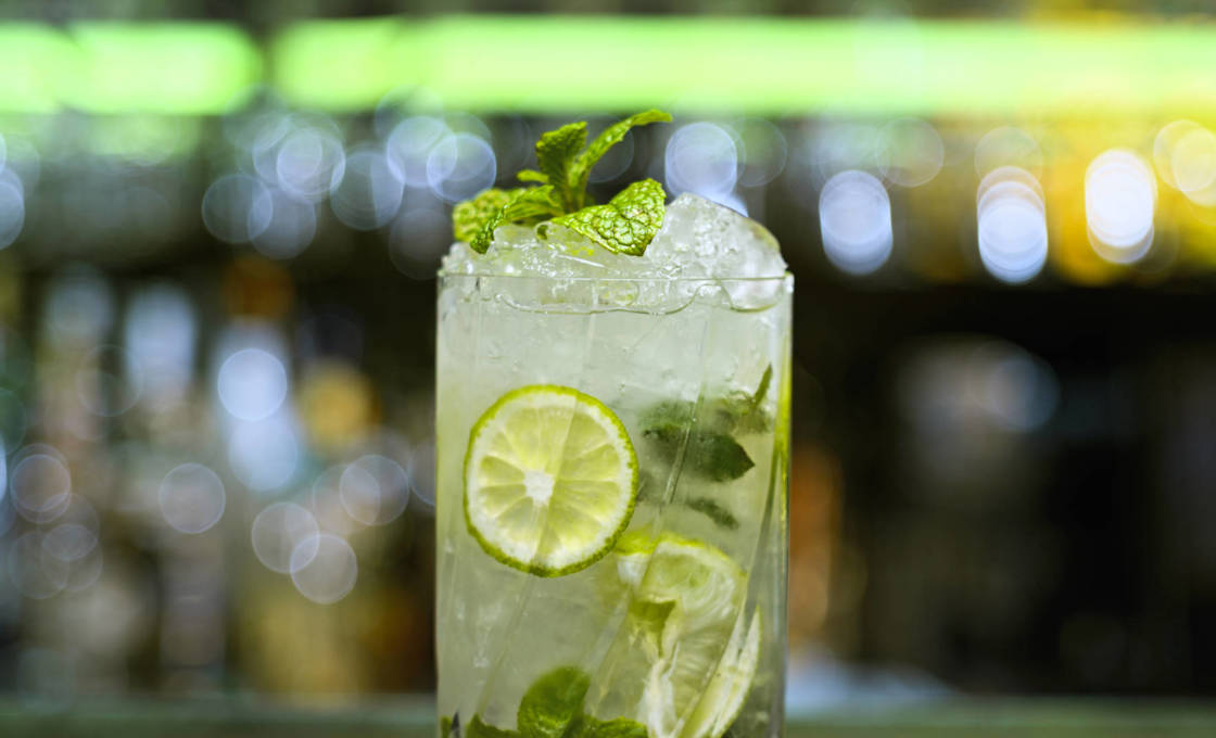 A glass of Caribbean cool with a bar out of focus behind