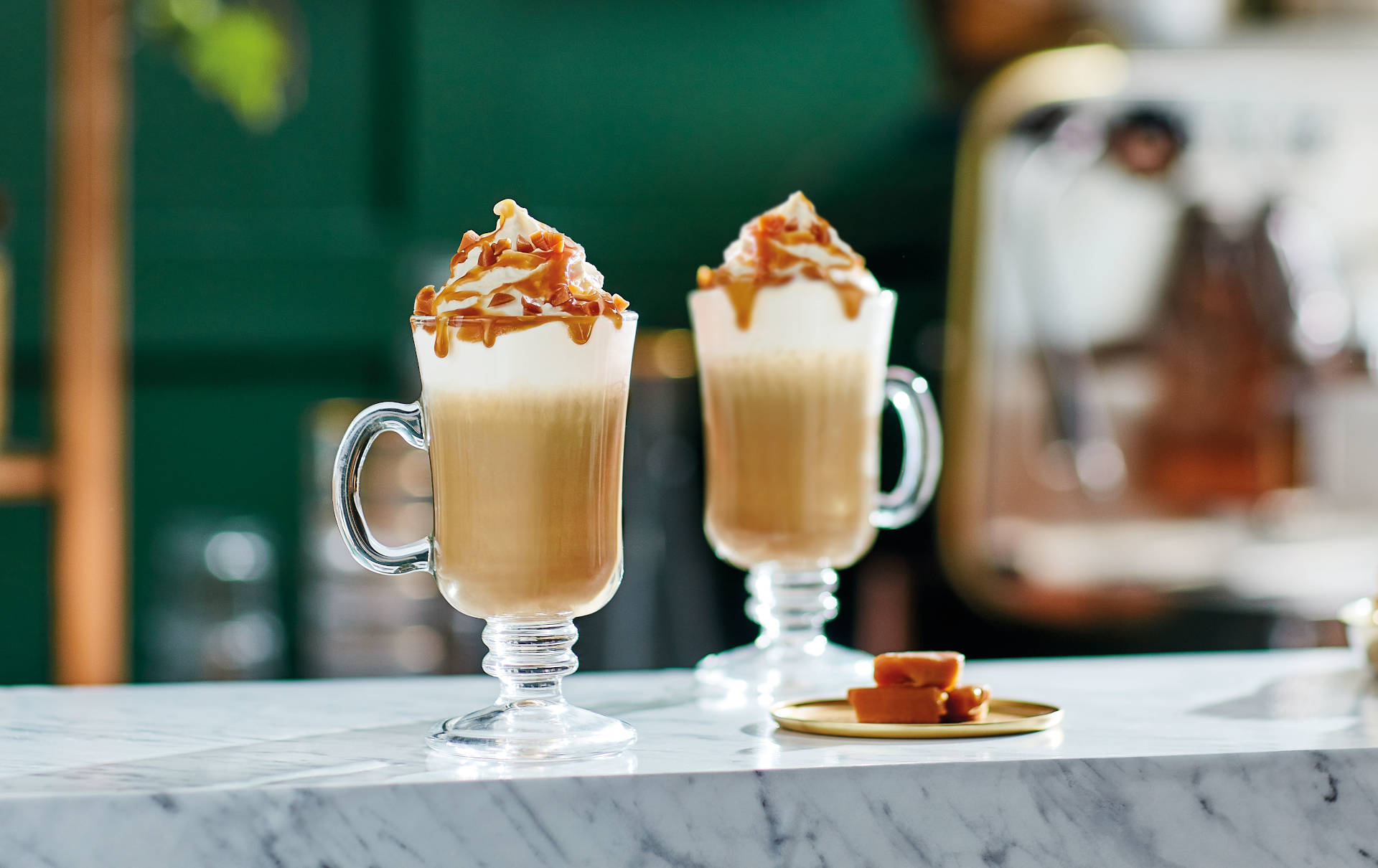 A glass of Iced Latte Deluxe with a straw and whipped cream on top