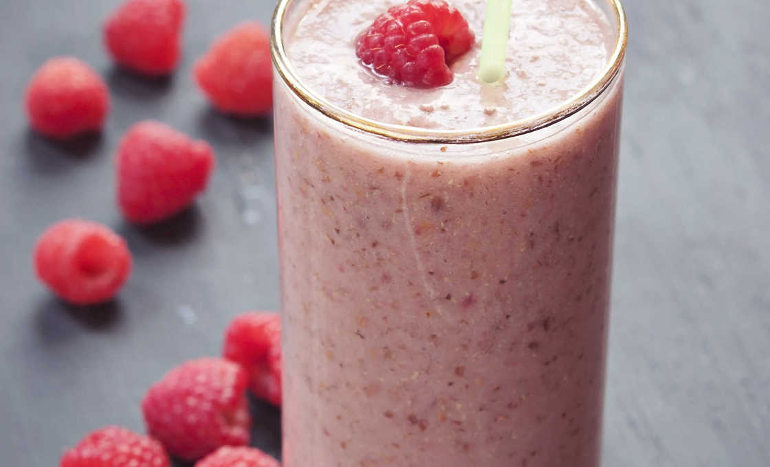 A glass of raspberry bubbleade with loose raspberries