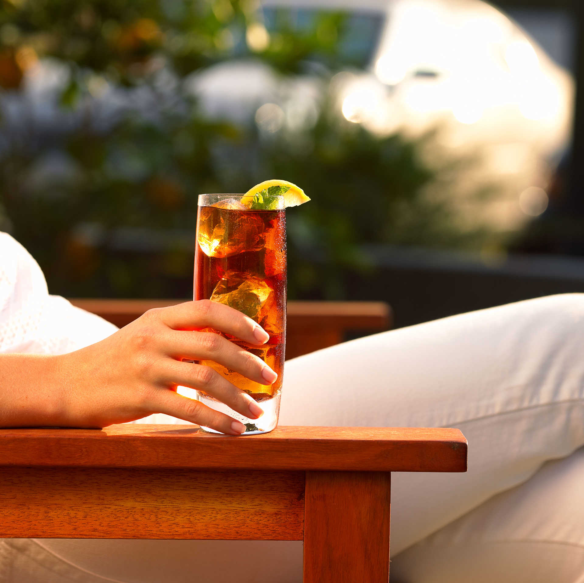 A person sitting down holding a glass of lemon pie caramel iced tea