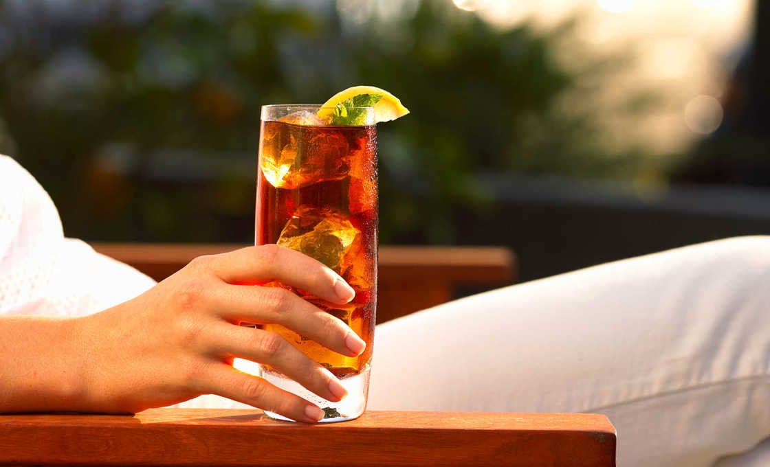 A person sitting down holding a glass of lemon pie caramel iced tea
