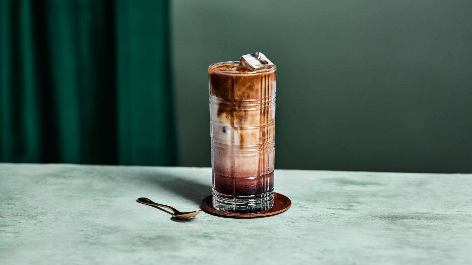 A glass of Dazzleberry iced latte with spoon and mat