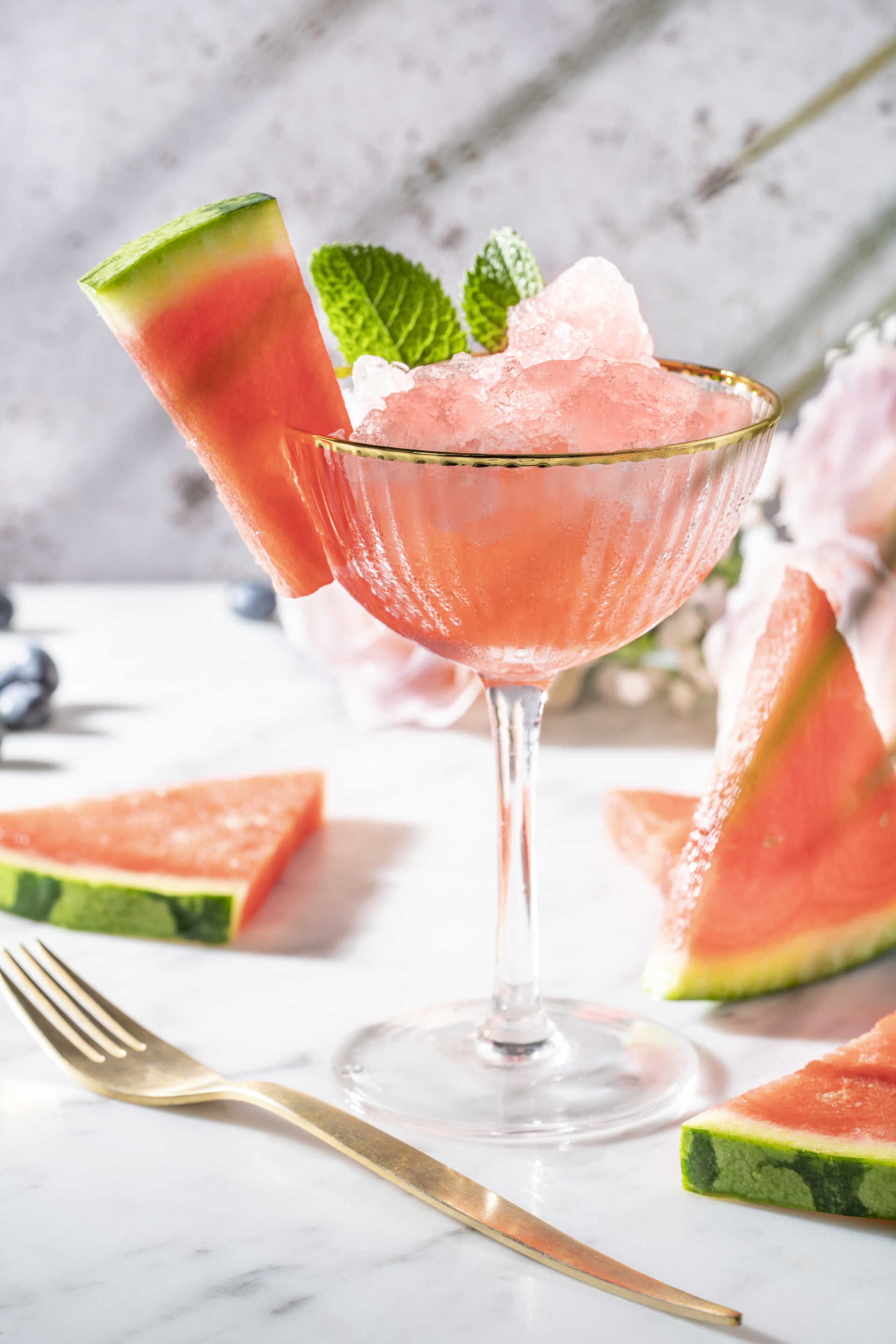 Temptation glass cup on marble table with watermelon slices and mint leaves