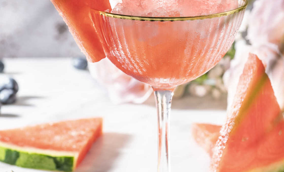 Temptation glass cup on marble table with watermelon slices and mint leaves