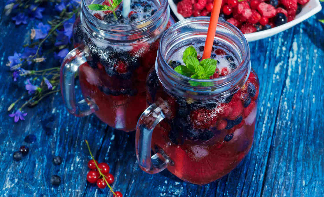 Two glasses of Blueberry Iced Tea on a table with blueberries in a bowl