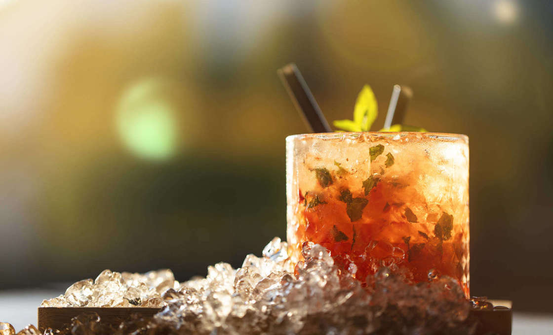 Glass of Violet And Cranberry Soda on a wooden board with ice