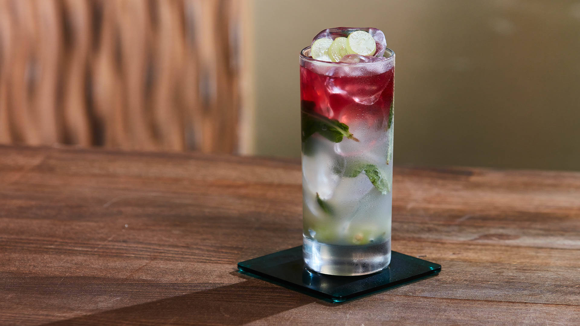 A glass of lavender fruit cooler on a coaster