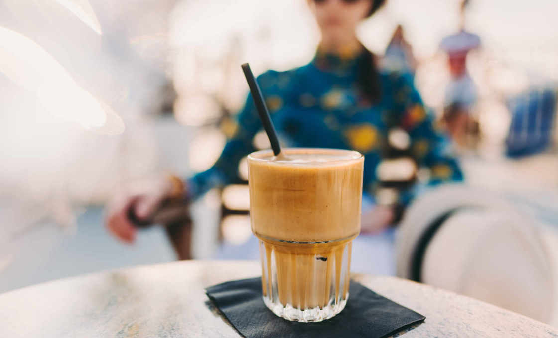 Glass of minty mocha on a table with a woman out of focus in the background