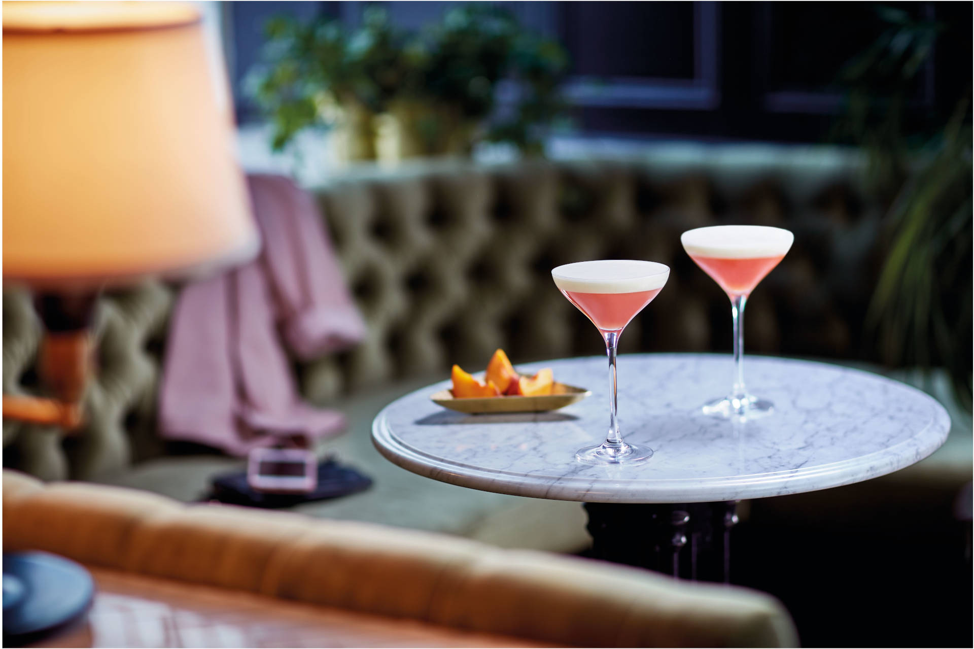 Two glasses of Peach on the Beach on a bar table with snacks