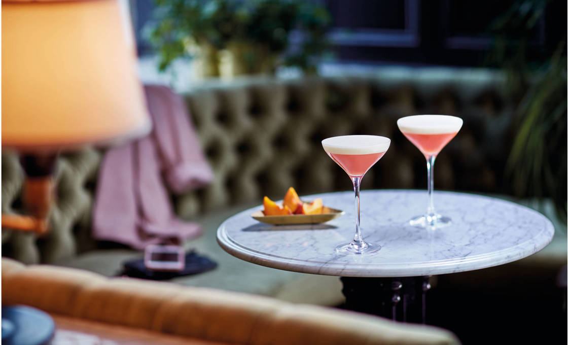 Two glasses of Peach on the Beach on a bar table with snacks